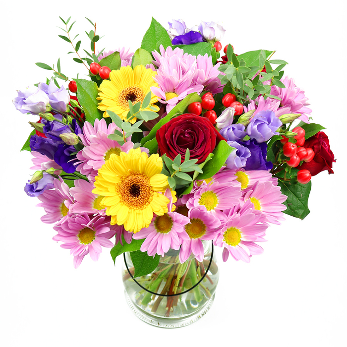 In this image, a lush, mixed bouquet rises generously from a clear glass vase set before a crisp white background, the kind of refined yet welcoming design that feels perfectly at home in a Chelsea sitting room overlooking the King's Road. At the core, deep red roses open in layered spirals, their velvety petals rich and saturated, adding romance and a touch of old-world charm. Flanking them, two bright yellow gerbera daisies with dark brown-orange centres stand out boldly, their broad, flat faces resembling miniature suns that infuse the arrangement with warmth and cheer. Around this central focus, soft pink daisies and chrysanthemums cluster thickly, each bloom made of numerous slender petals encircling a yellow centre, building a cushion of pastel tones that softens the stronger colours. Interlaced through the arrangement are refined purple and lavender lisianthus, their bell-shaped blossoms and gently curled edges offering a cool, contemporary elegance, like the subtle tones in a modern Chelsea gallery. Small, glossy red Hypericum berries nestle between the petals on slender stems, scattered accents that add texture and an almost jewel-like sparkle. A variety of green foliage supports and frames the blooms: broad, dark leaves give structure and shadow, while lighter, more delicate sprigs create movement and a sense of freshly gathered growth, reminiscent of a walk through nearby Ranelagh Gardens. The clear vase reveals straight, carefully trimmed stems immersed in clean water, underscoring the professional attention to detail. Overall, the bouquet feels full and celebratory, a versatile design ideal for birthdays, thank-you gifts, or simply bringing colour and life into a Chelsea home with reliable local flower delivery.